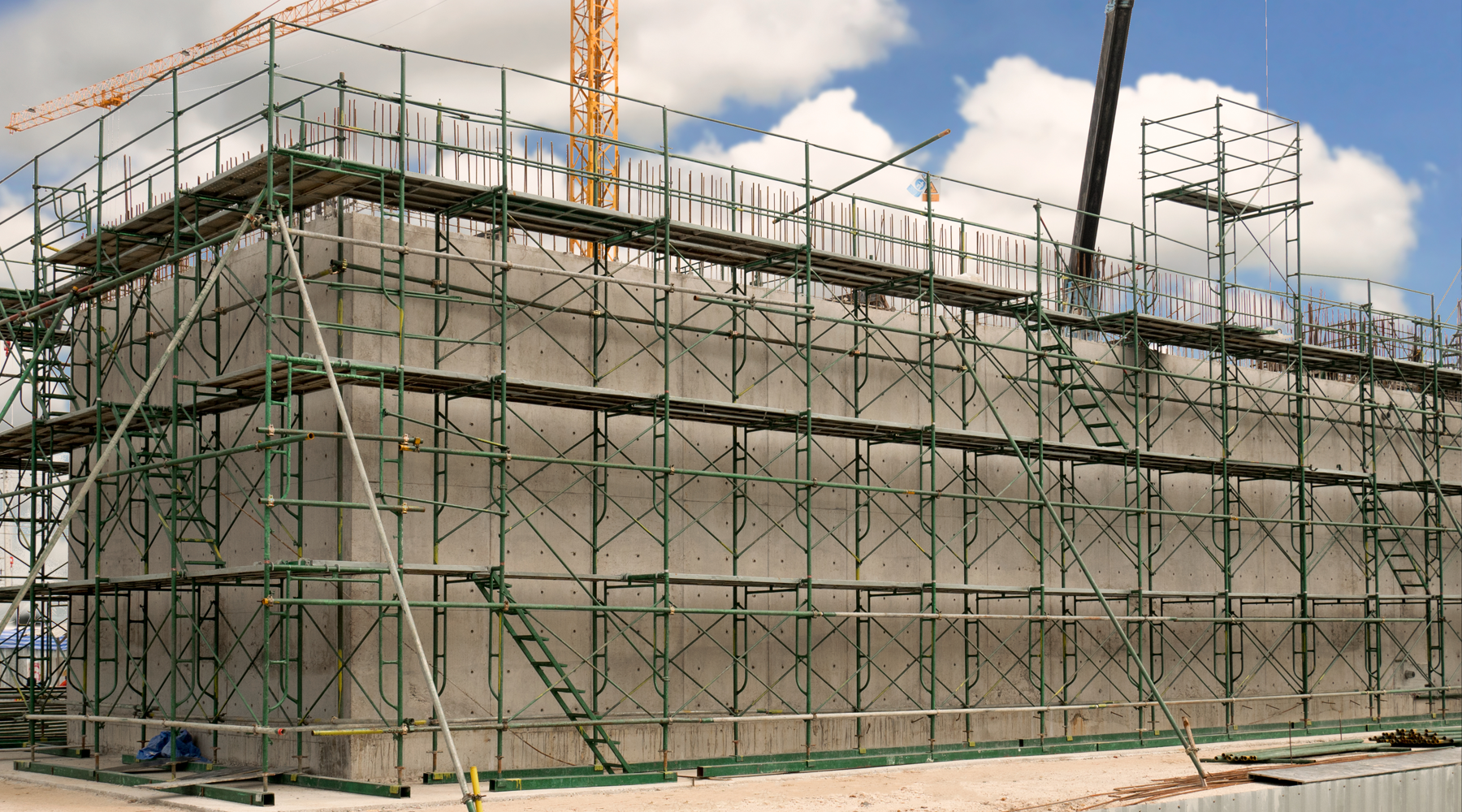Industrial concrete building construction with green metal scaffolding
