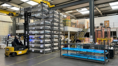Yellow forklift stacking crates in a large industrial warehouse.